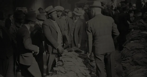 Vintage black-and-white photograph depicting a bustling historical tobacco market scene, showcasing workers and buyers interacting over bundles of tobacco leaves, capturing the rich heritage of the cigar industry.